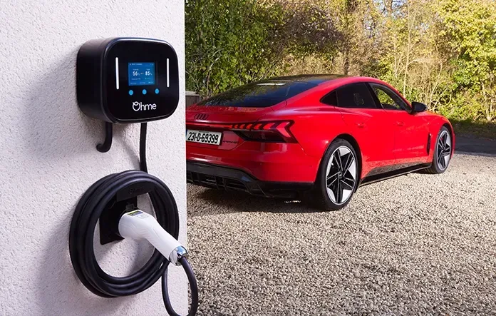Ohme Home Pro EV charger mounted on a home wall, charging a red Audi.
